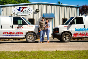 JTech owners standing in front of the work trucks with a metal building behind them