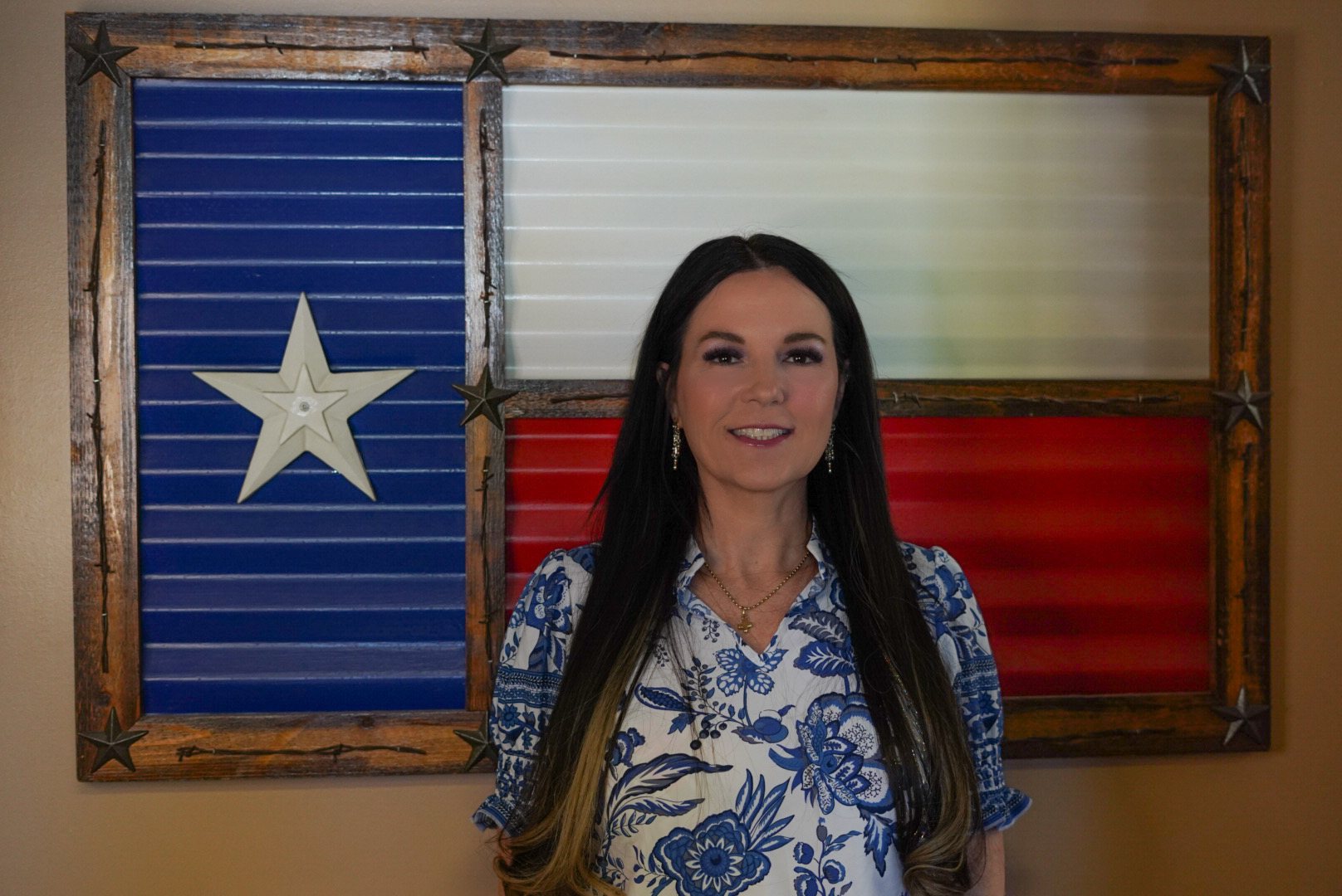 Jennifer standing in front of a metal Texas flag